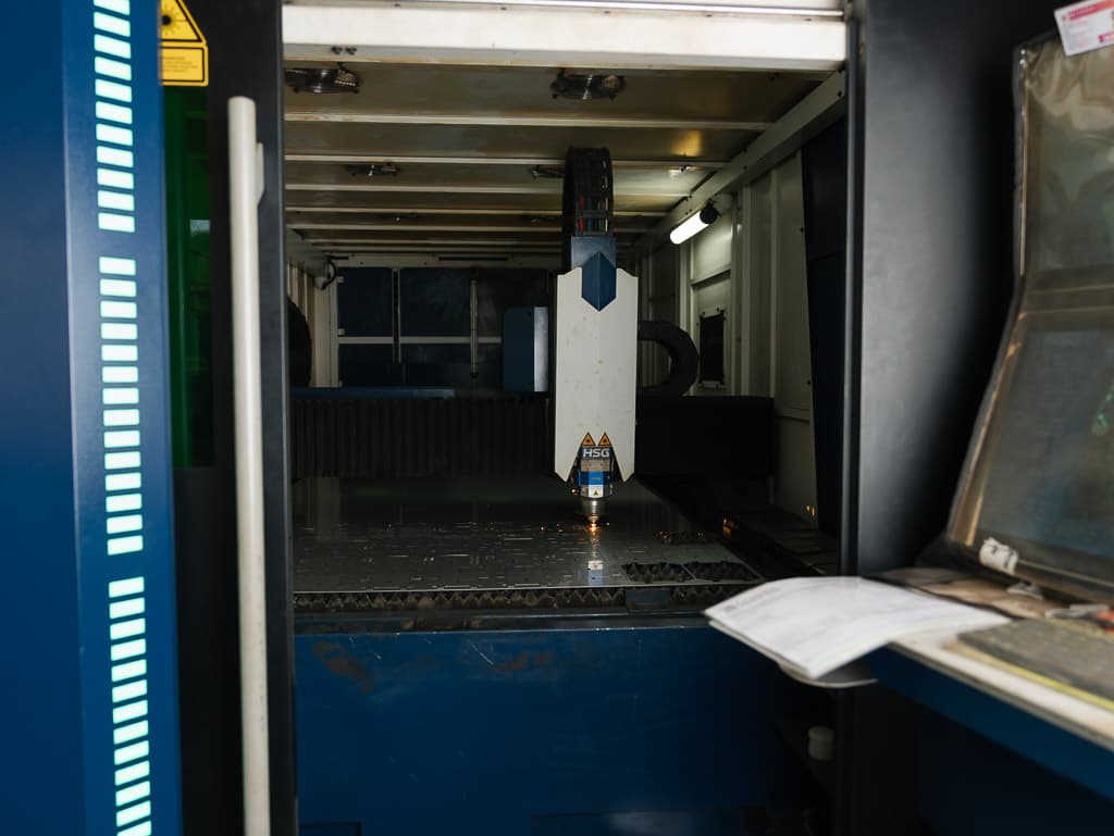 Close-up of the fibre laser cutting head over a nested sheet