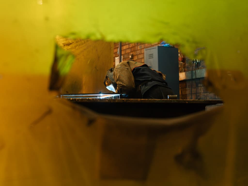 Welder working on a clamped fixture with a live arc