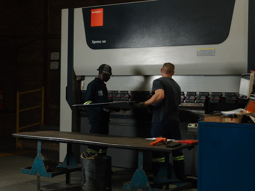 Two operators bending a long sheet on the press brake
